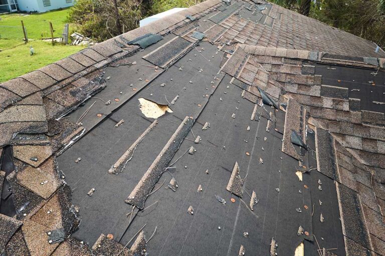 Close view of curled and cracked asphalt shingles on a weathered residential roof.